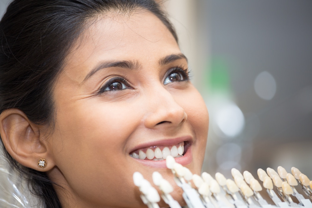 A woman smiling while having porcelain veneers matched to her teeth.